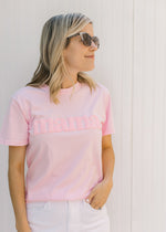 Model wearing a pink short sleeve tee shirt with Mama across the front in puff white letters.