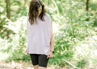 Brunette model wearing oversized pink workout shirt and bike shorts.