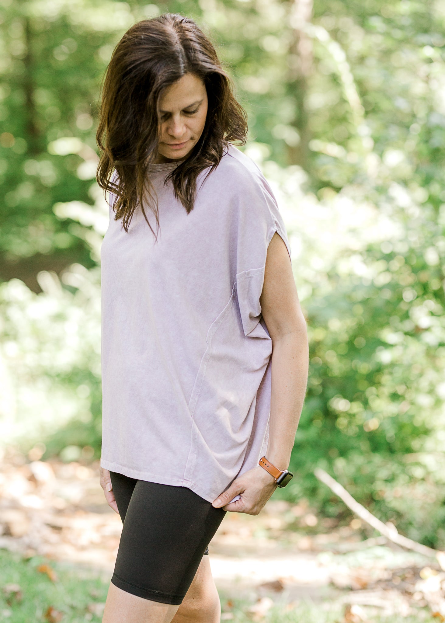 Brunette model wearing pink workout shirt and bike shorts.