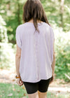 BAck view of xBrunette model wearing pink workout shirt and bike shorts.