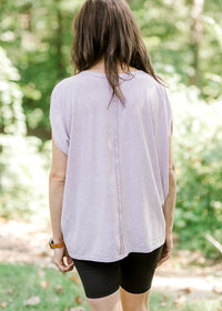 BAck view of xBrunette model wearing pink workout shirt and bike shorts.