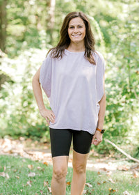 Brunette model wearing pink workout shirt and bike shorts and sneakers.