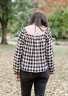 Back view of Brunette model wearing cream and black plaid top.