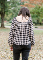 Back view of Brunette model wearing cream and black plaid top.