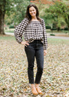 Brunette model wearing cream and black plaid top with jeans and heeled mules.