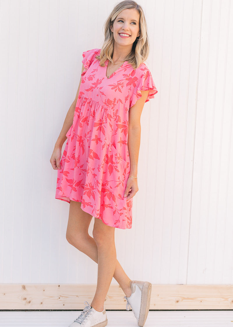 Model wearing sneakers with a pink dress with a dark pink floral pattern and a babydoll fit. 