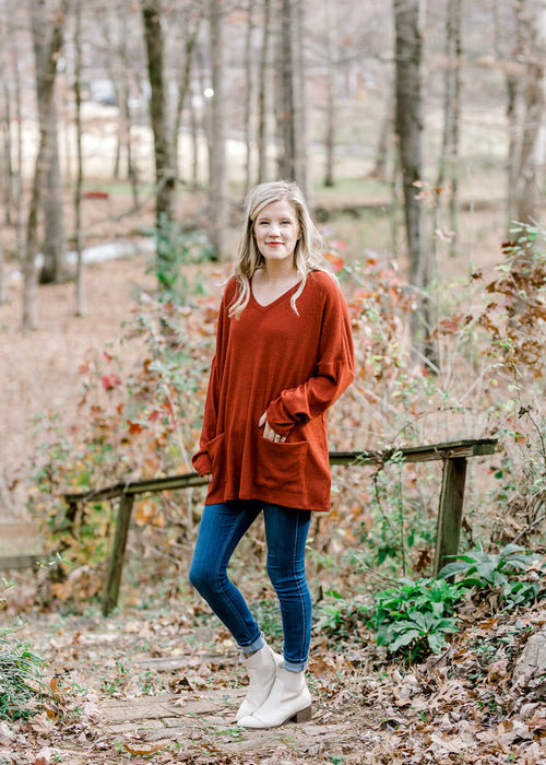 Blonde model wearing deep rust long sleeve top.