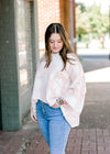 Brunette model wearing pink and white sweater.