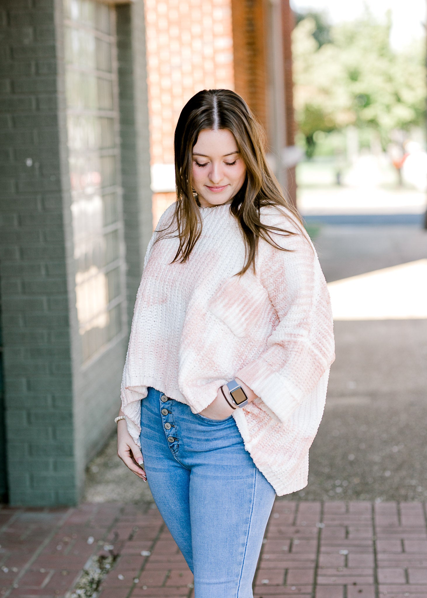 Brunette model wearing pink and white sweater.