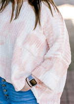 Close up view of sleeve and pocket on pink and white sweater.