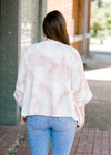 Back view of Brunette model wearing pink and white sweater.