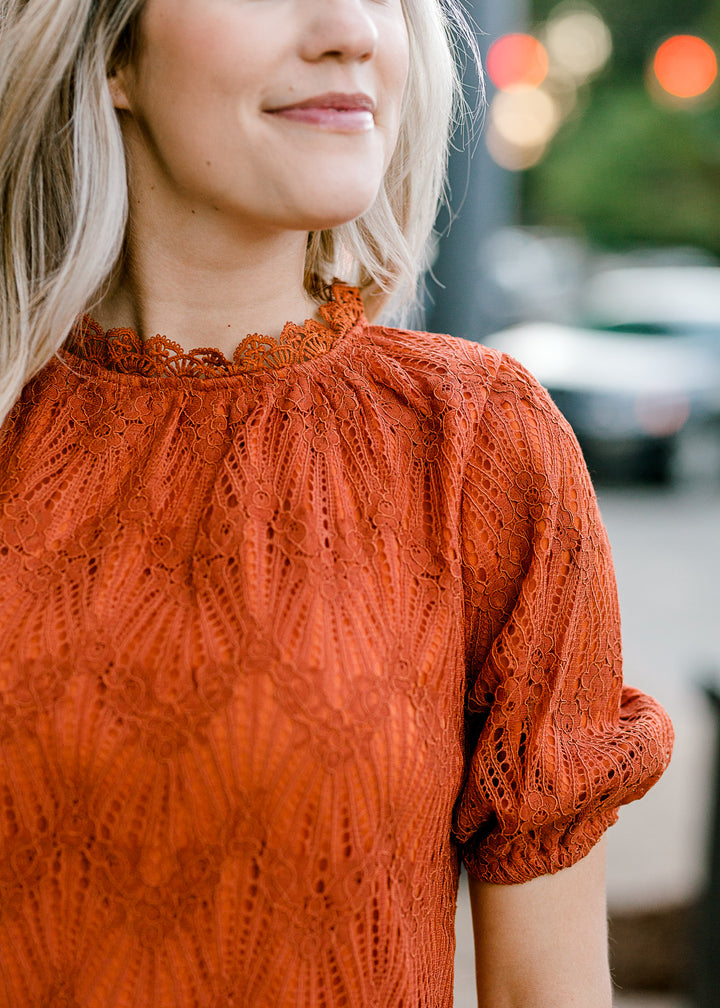 Close up view of lace overlay on rust top.