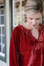 Blonde model wearing red velvet top with drawstring neck.
