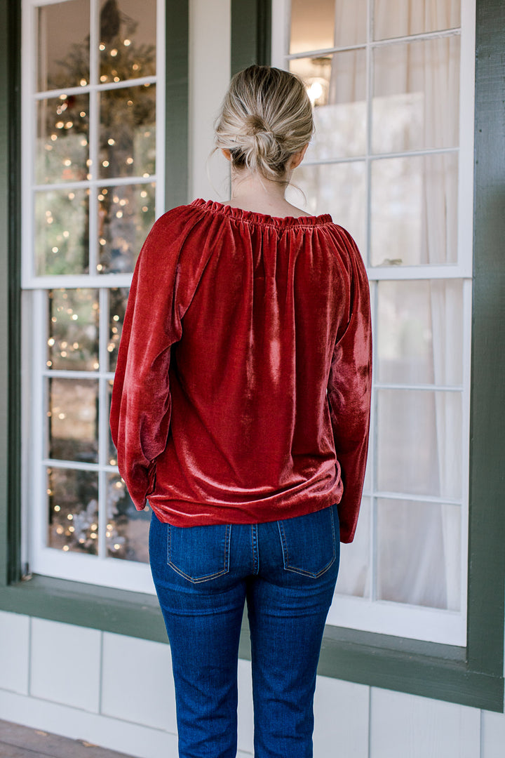 BAck view of Blonde model wearing red velvet top with drawstring neck.