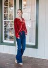 Blonde model wearing red velvet top with drawstring neck and long sleeves.