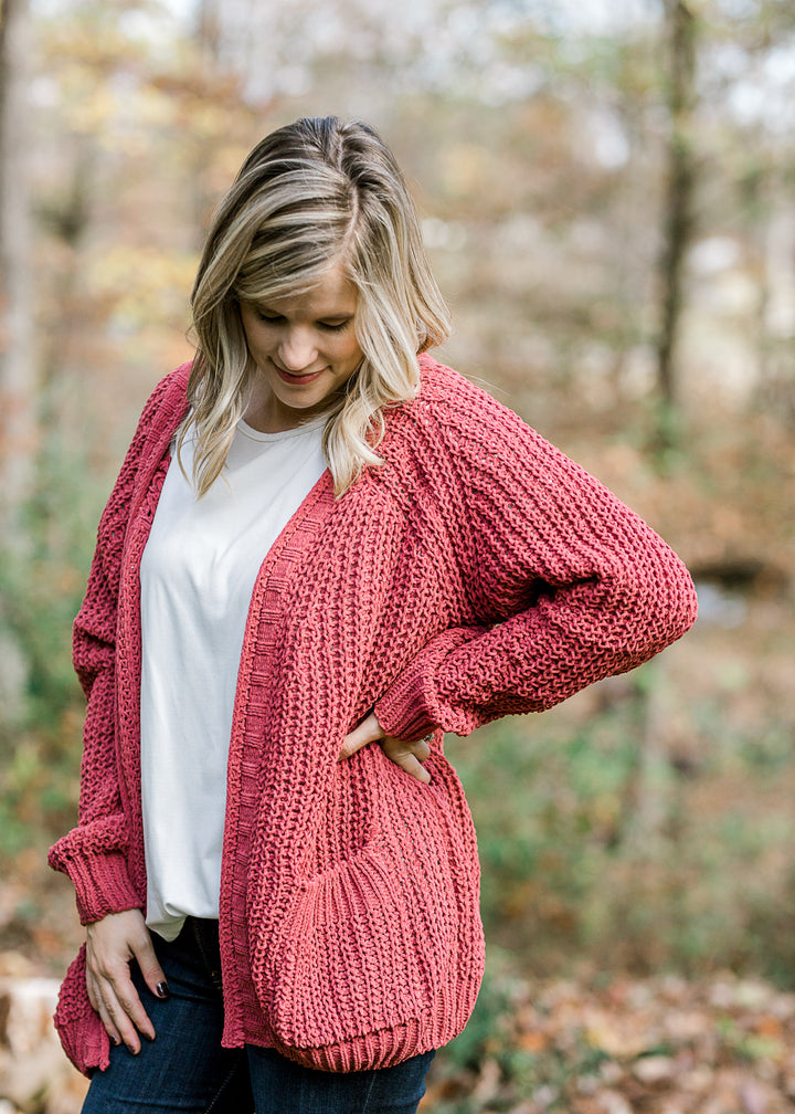 Blonde model wearing a rust cable knit cardigan with a white top. 