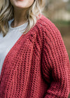Close up view of Blonde model wearing a rust cable knit cardigan