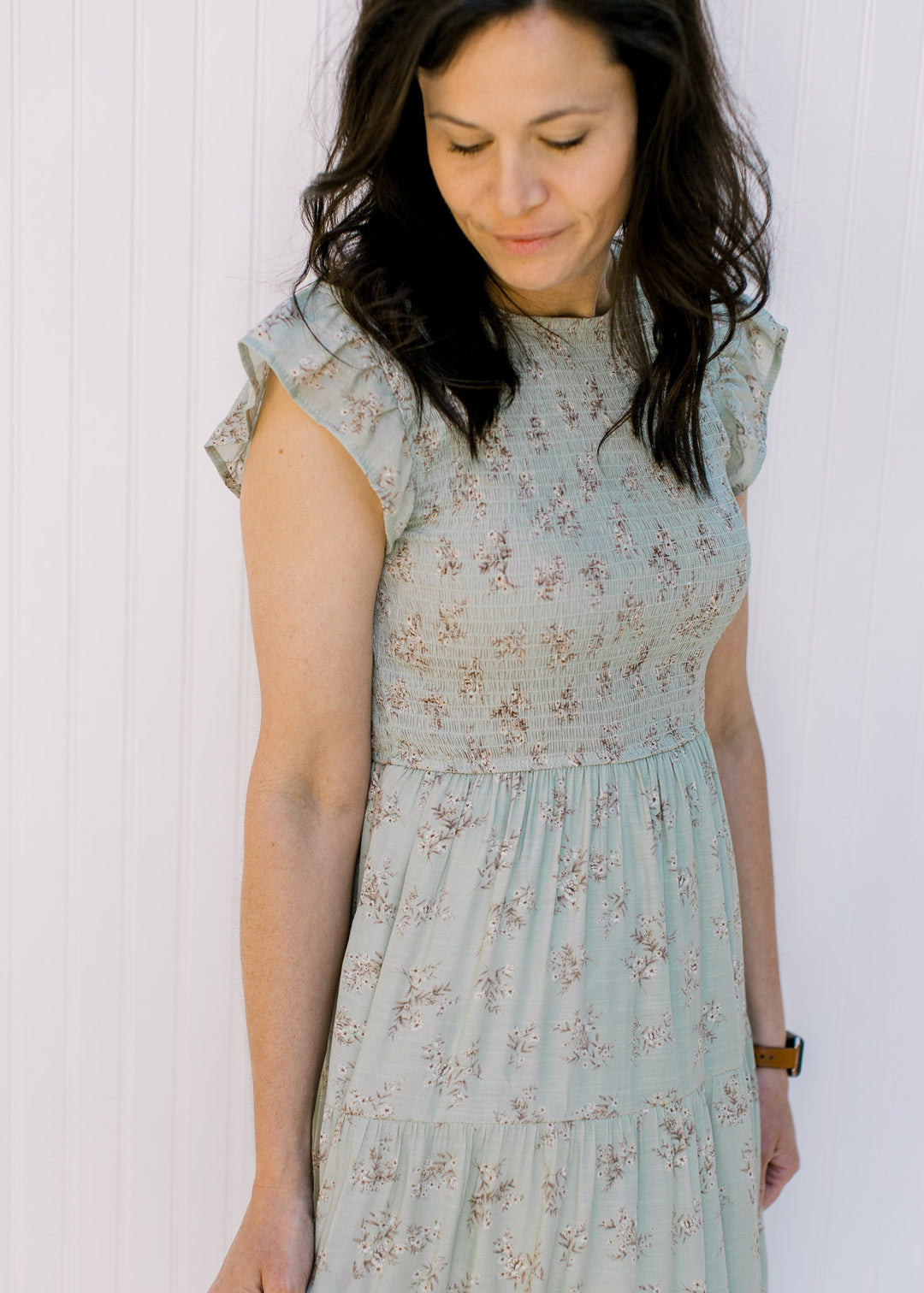 Close up view of Model wearing a sage tiered midi dress with a smocked bodice and flutter sleeves.
