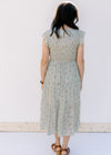 Back view of Model wearing a sage tiered midi dress with a smocked bodice and flutter sleeves.