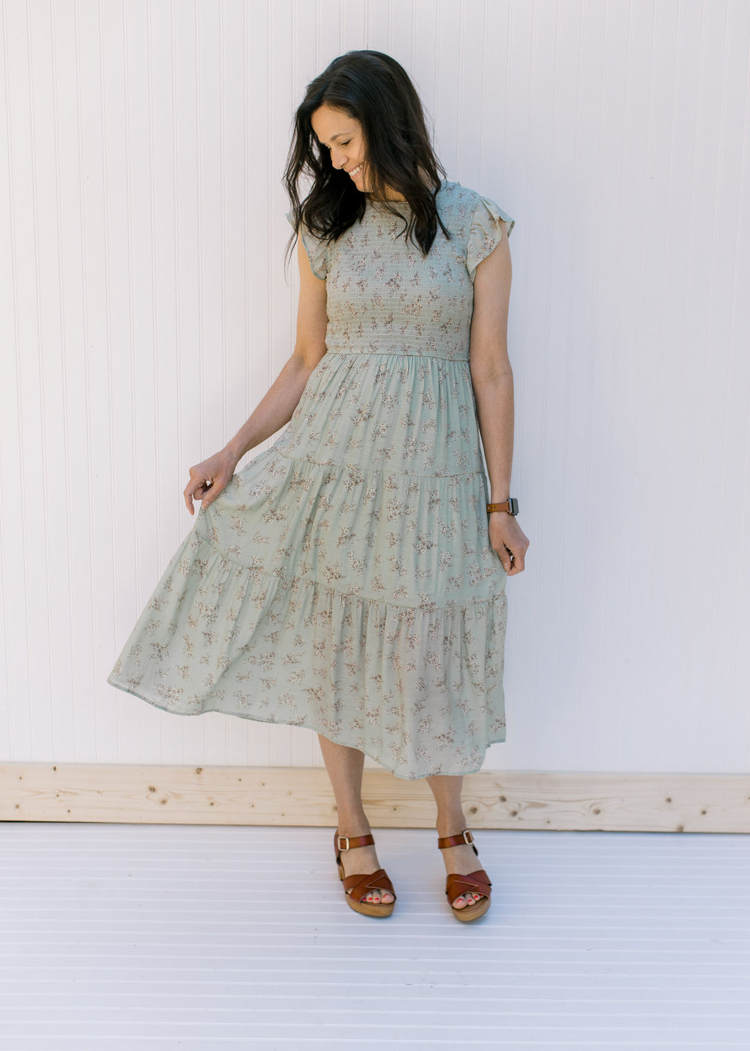 Model wearing a sage tiered midi dress with a smocked bodice and flutter capped sleeves. 