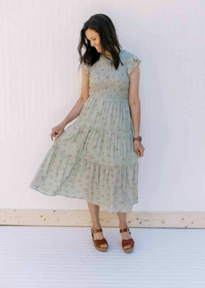 Model wearing a sage tiered midi dress with a smocked bodice and flutter capped sleeves. 