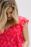 Close up view of Blonde model wearing a bright pink top with capped sleeves.