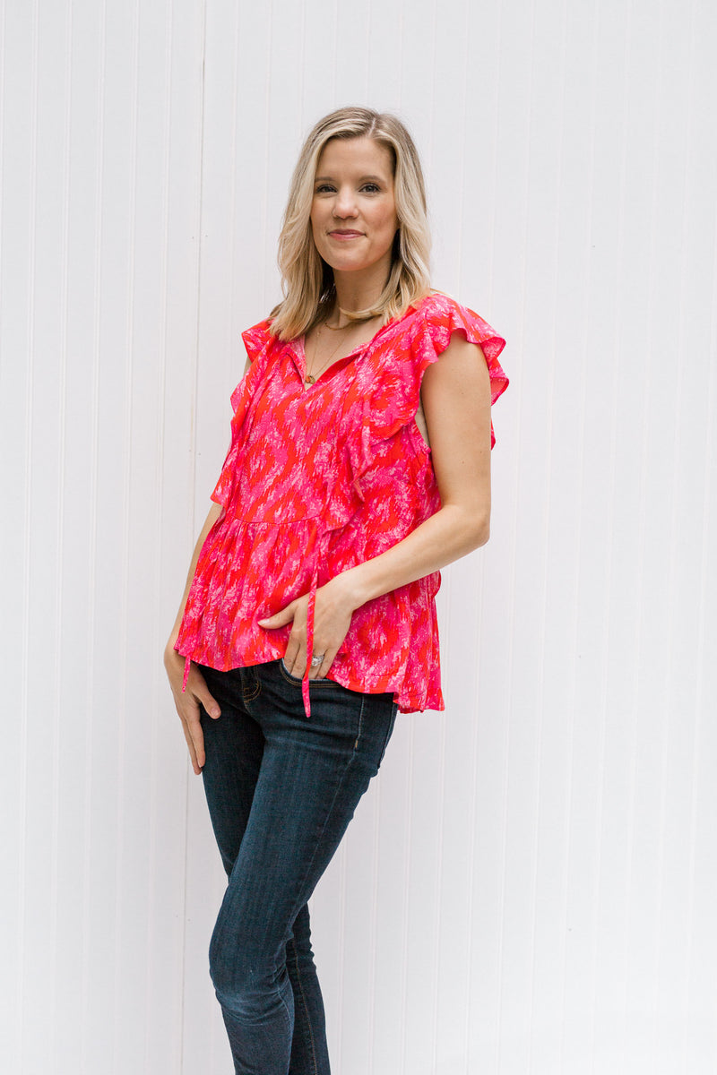 Blonde model wearing jeans with a bright pink top with capped sleeves.