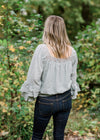 Back view of Blonde model wearing sea foam blouse with elastic waistband.