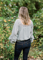 Back view of Blonde model wearing sea foam blouse with elastic waistband.