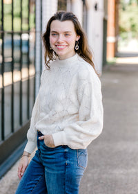 Brunette model wearing cream sweater.