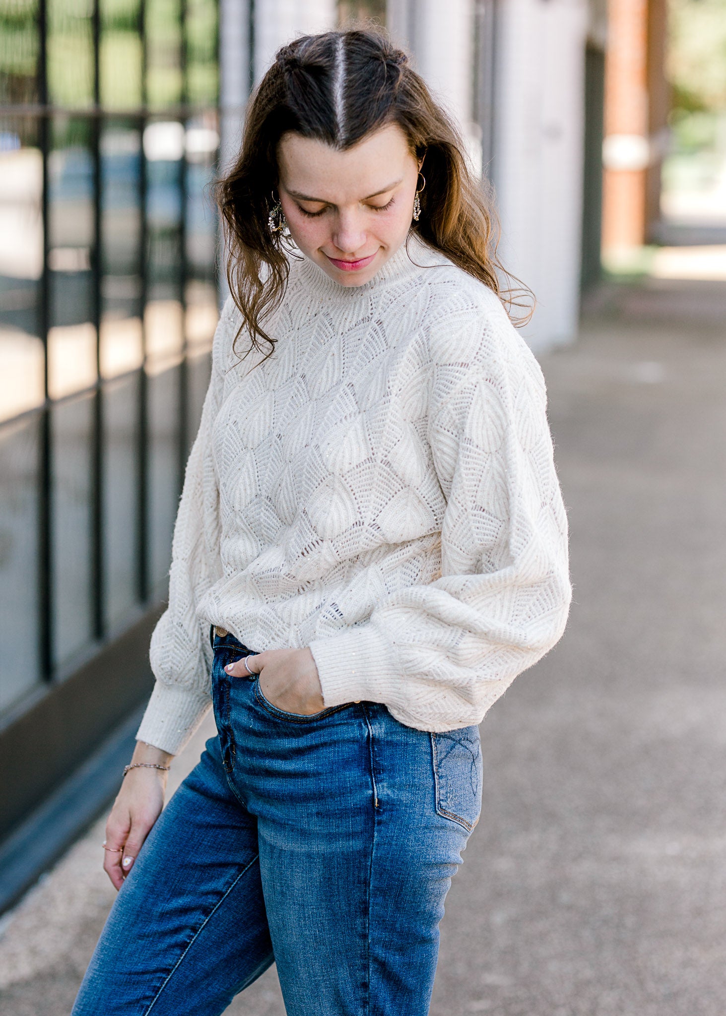 Brunette model wearing cream sweater with shell stitching.