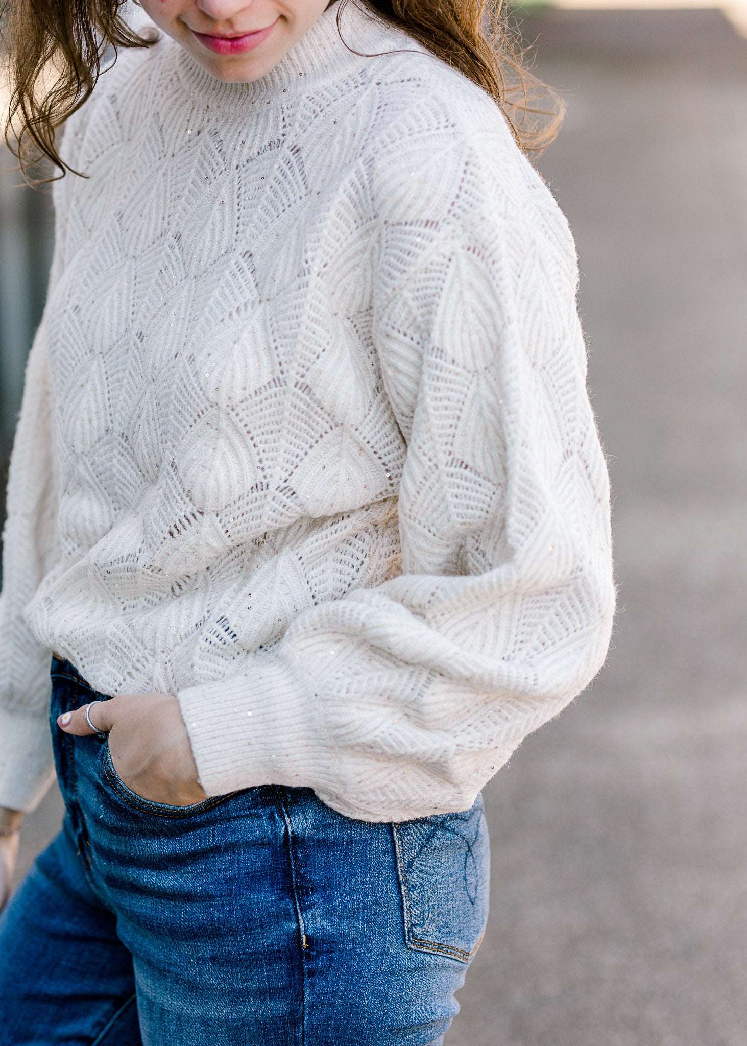Brunette model wearing cream sweater with bubble long sleeves.