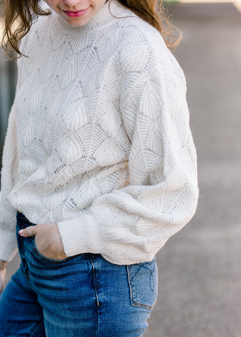 Brunette model wearing cream sweater with bubble long sleeves.