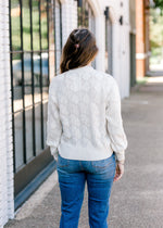 Back view of Brunette model wearing cream sweater.