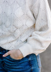Close up view of shell stitching on cream sweater.