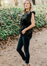 Blonde model wearing iridescent black top and jeans.