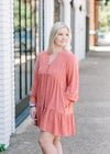 Blonde model wearing tiered, burnt coral dress.