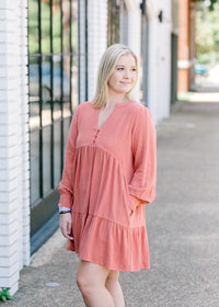 Blonde model wearing tiered, burnt coral dress.