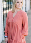 Blonde model wearing burnt coral dress with three detail buttons.
