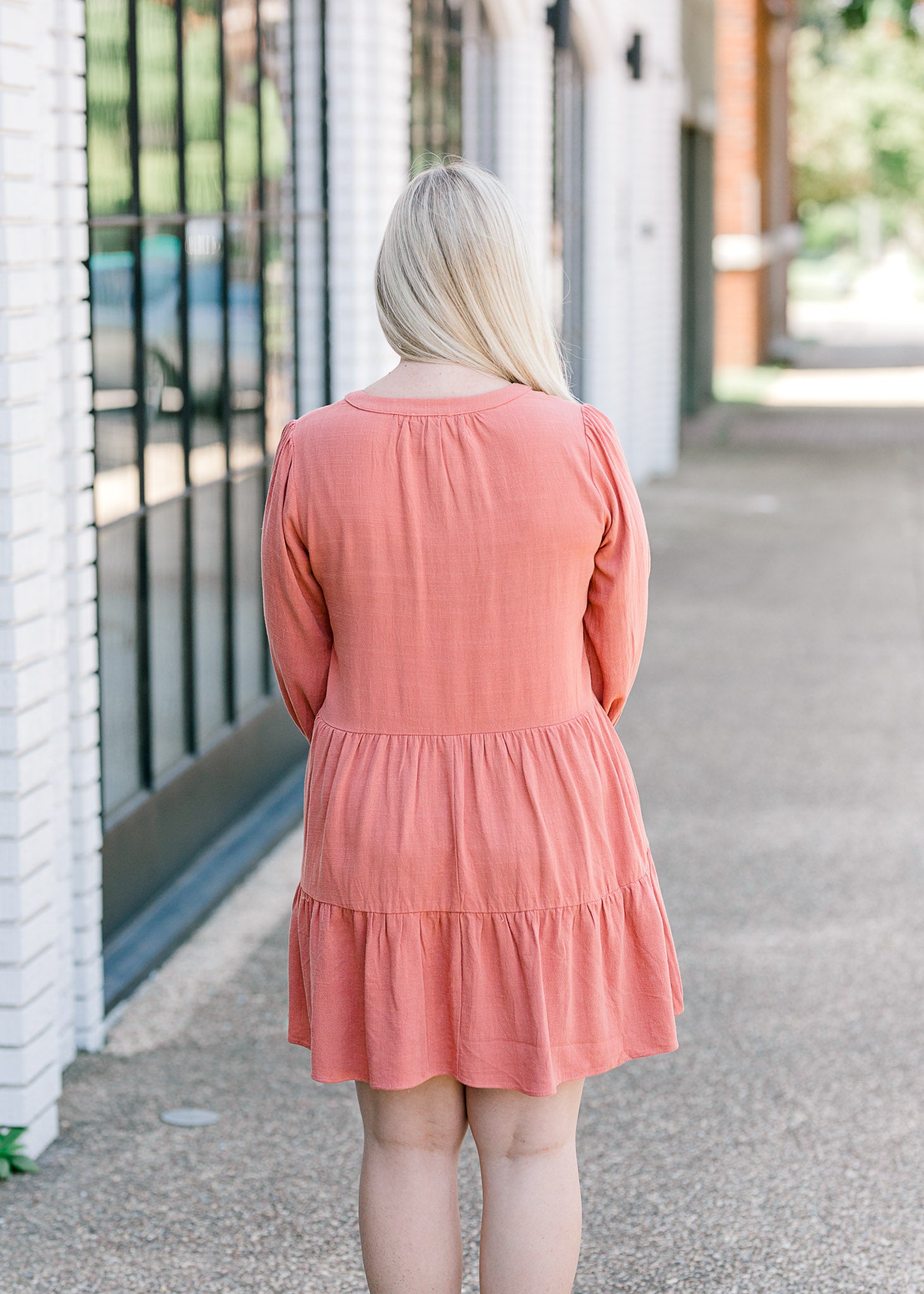Back view of Blonde model wearing burnt coral dress.