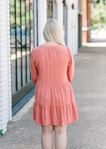Back view of Blonde model wearing burnt coral dress.