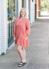 Blonde model wearing burnt coral dress with sandals.