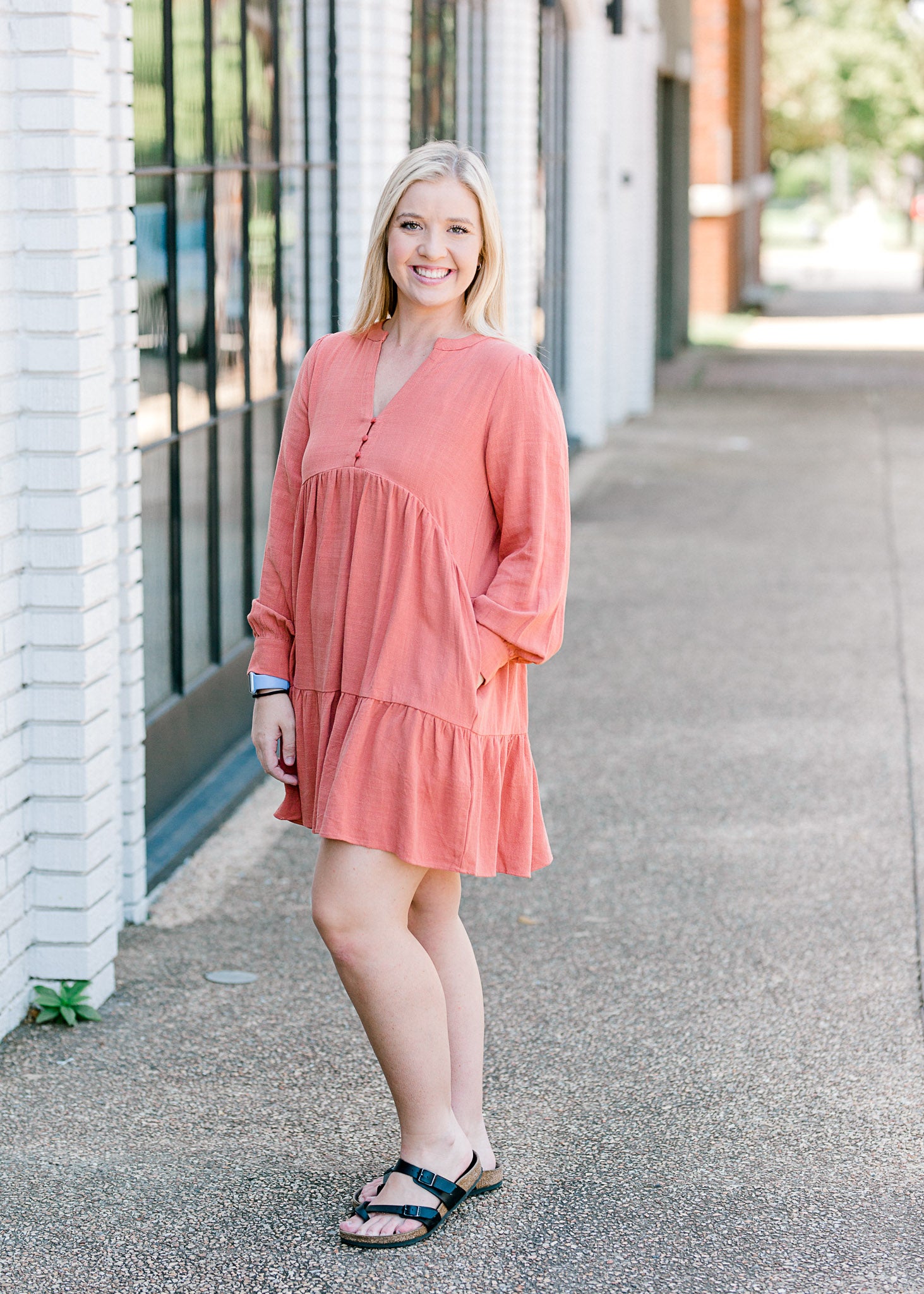 Blonde model wearing burnt coral dress with sandals.