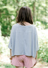 Back view of brunette model wearing silver workout shirt.