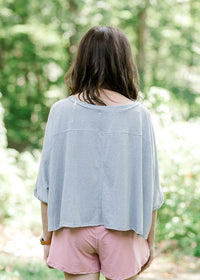 Back view of brunette model wearing silver workout shirt.