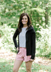 Brunette model wearing silver workout shirt, shorts and jacket.