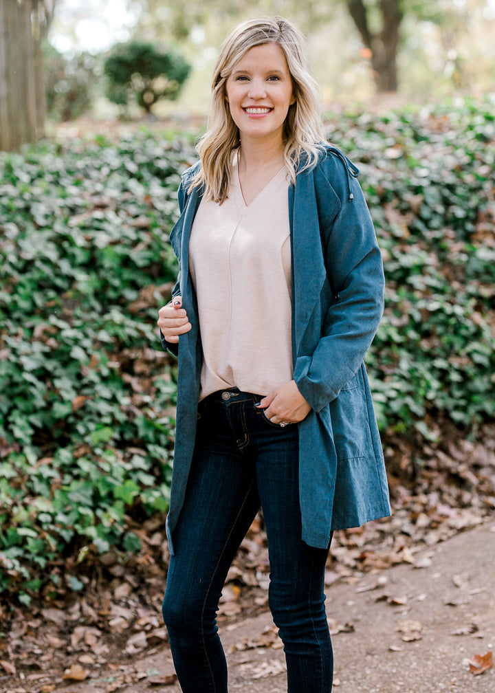 Blonde model wearing a hooded slate blue jacket. 
