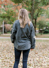 Back view of Blonde model wearing slate blue sweater with cream star detail on sleeve.