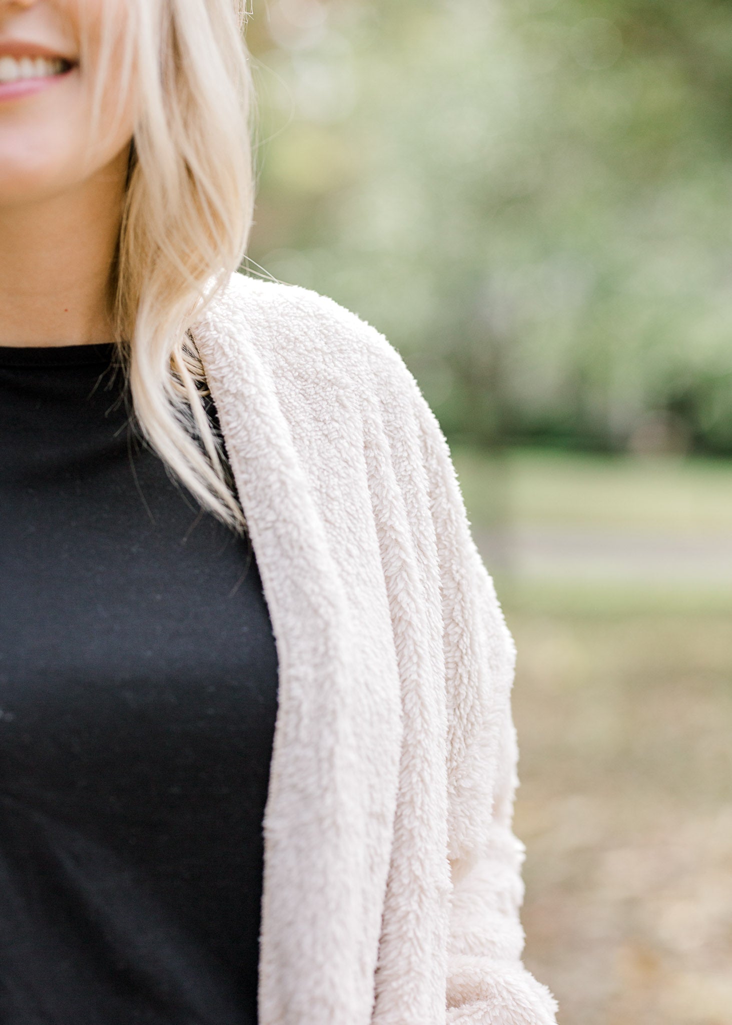 Shoulder detail of Blonde model is soft cream cardigan.