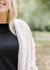 Shoulder detail of Blonde model is soft cream cardigan.